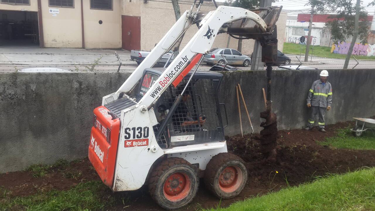 Bobcat com perfuratriz fazendo escavação de estacas em Curitiba